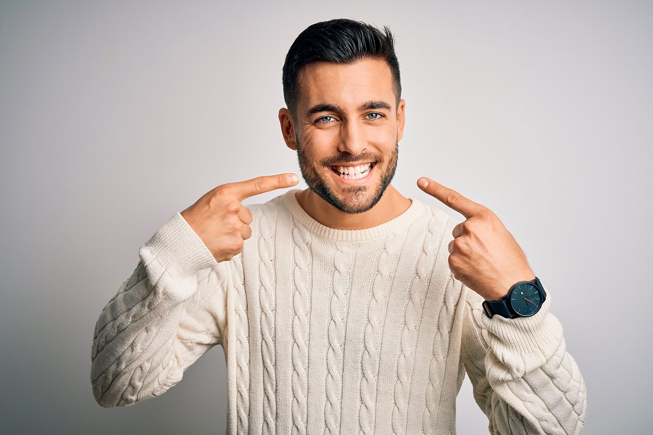 Patient smiling and pointing to his tooth