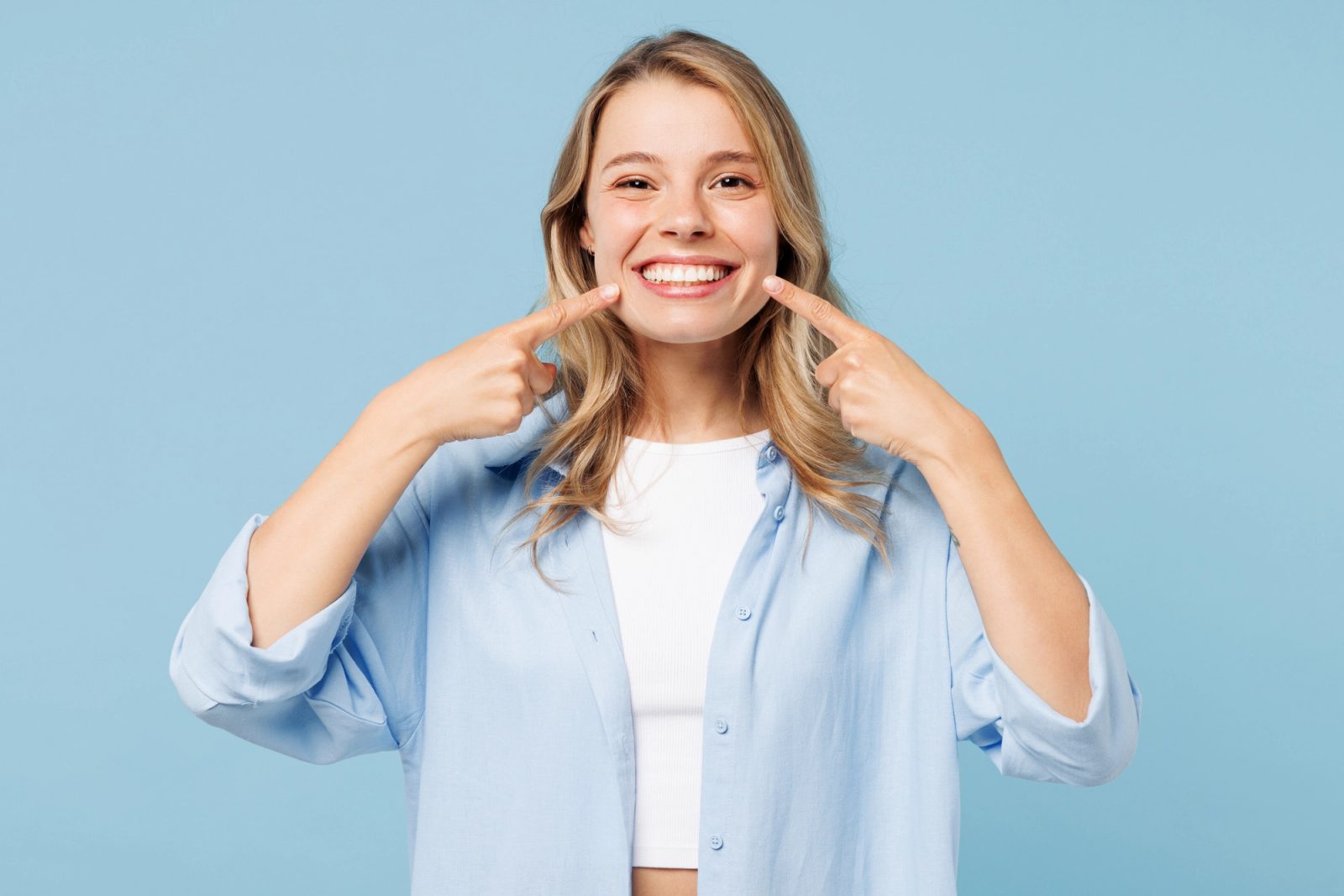 Patient smiling and pointing to her tooth